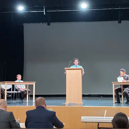A student speaking at a lectern during a house debating competition