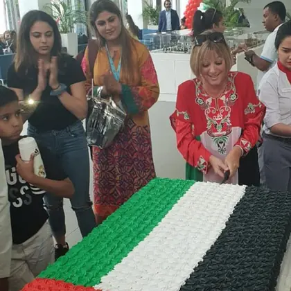 Students in traditional dress with flags and a decorated display for National Day